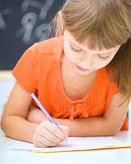 Image showing Little girl is writing using a pen