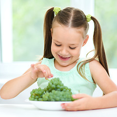 Image showing Cute little girl is eating green grapes