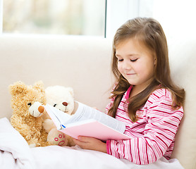 Image showing Little girl is reading a story for her teddy bears