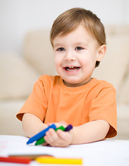 Image showing Little boy is drawing on white paper