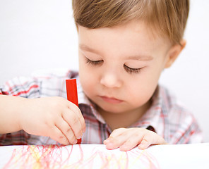 Image showing Little boy is drawing on white paper