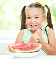 Image showing Cute little girl is eating watermelon