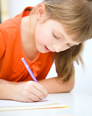 Image showing Little girl is writing using a pen