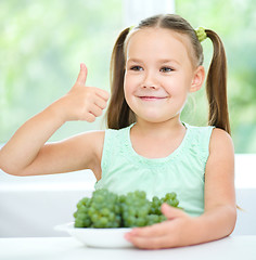 Image showing Cute little girl is eating green grapes