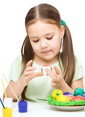 Image showing Little girl is painting eggs preparing for Easter