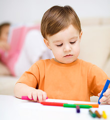 Image showing Little boy is drawing on white paper