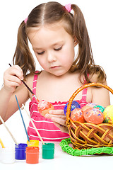 Image showing Little girl is painting eggs preparing for Easter