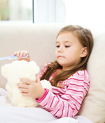 Image showing Little girl is brushing her teddy bear