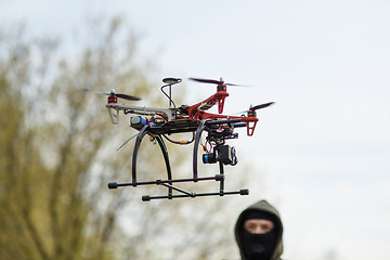 Image showing Man in mask operating a drone with remote control.