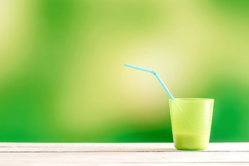 Image showing Green cup with a blue straw