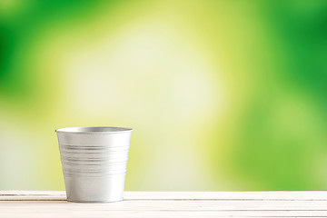 Image showing Metal bucket on a wooden desk