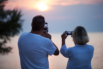 Image showing Back view of couple taking photos of sunset