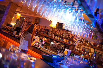 Image showing Young woman enjoying a drink in a cocktail bar