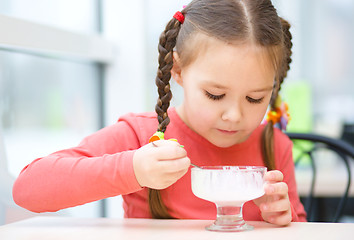 Image showing Little girl is eating ice-cream in parlor