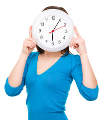 Image showing Young woman is holding big clock