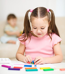 Image showing Little girl is playing with plasticine