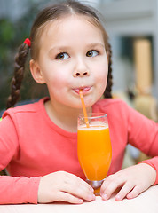 Image showing Little girl is drinking orange juice