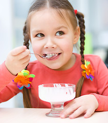 Image showing Little girl is eating ice-cream in parlor