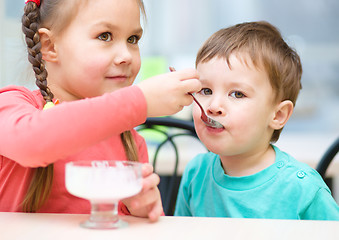 Image showing Girl is feeding his little brother with ice-cream