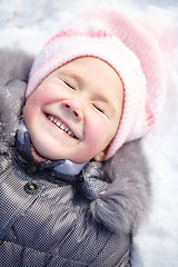 Image showing Little girl is laying on a snow