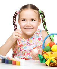 Image showing Little girl is painting eggs preparing for Easter