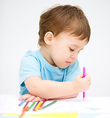 Image showing Little boy is drawing on white paper