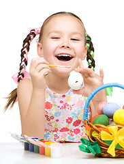 Image showing Little girl is painting eggs preparing for Easter