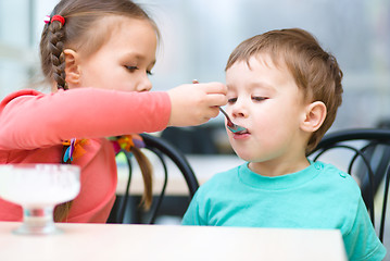 Image showing Girl is feeding his little brother with ice-cream
