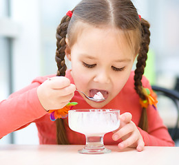 Image showing Little girl is eating ice-cream in parlor