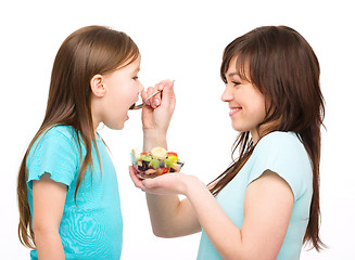 Image showing Mother is feeding her daughter with fruit salad