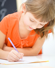 Image showing Little girl is writing using a pen