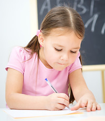 Image showing Little girl is writing using a pen