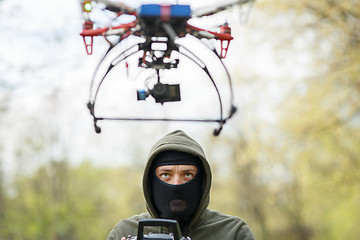 Image showing Man in mask operating a drone with remote control.