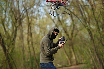 Image showing Man in mask operating a drone with remote control.