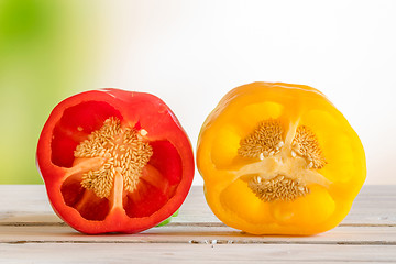 Image showing Red and yellow pepper with seeds on a wooden table