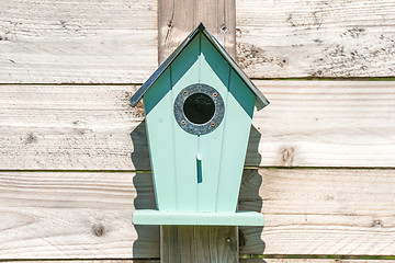 Image showing Blue birdhouse on a wooden fence