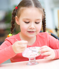 Image showing Little girl is eating ice-cream in parlor