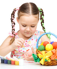 Image showing Little girl is painting eggs preparing for Easter