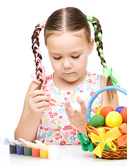 Image showing Little girl is painting eggs preparing for Easter