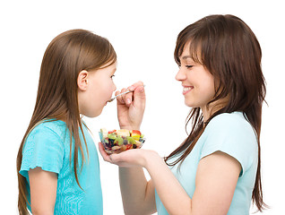 Image showing Mother is feeding her daughter with fruit salad