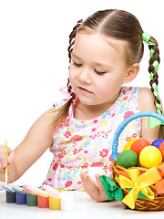 Image showing Little girl is painting eggs preparing for Easter