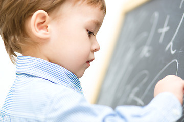 Image showing Little boy is writing on blackboard