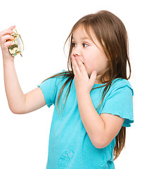 Image showing Little girl is looking at alarm clock