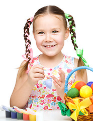 Image showing Little girl is painting eggs preparing for Easter