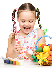 Image showing Little girl is painting eggs preparing for Easter