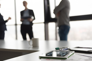 Image showing close up of tablet, business people on meeting in background