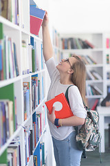 Image showing famale student selecting book to read in library