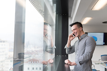 Image showing young business man speaking on  smart phone at office