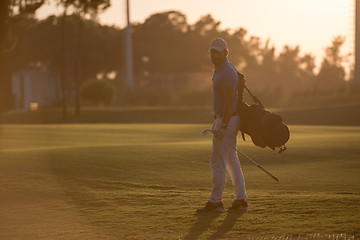 Image showing golfer  walking and carrying golf  bag at beautiful sunset