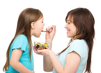 Image showing Mother is feeding her daughter with fruit salad